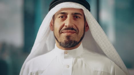 portrait of successful arab businessman in traditional outfit gently smiling, wearing white kandura and black agal keeping a ghutra in place. saudi, emirati, arab businessman concept.