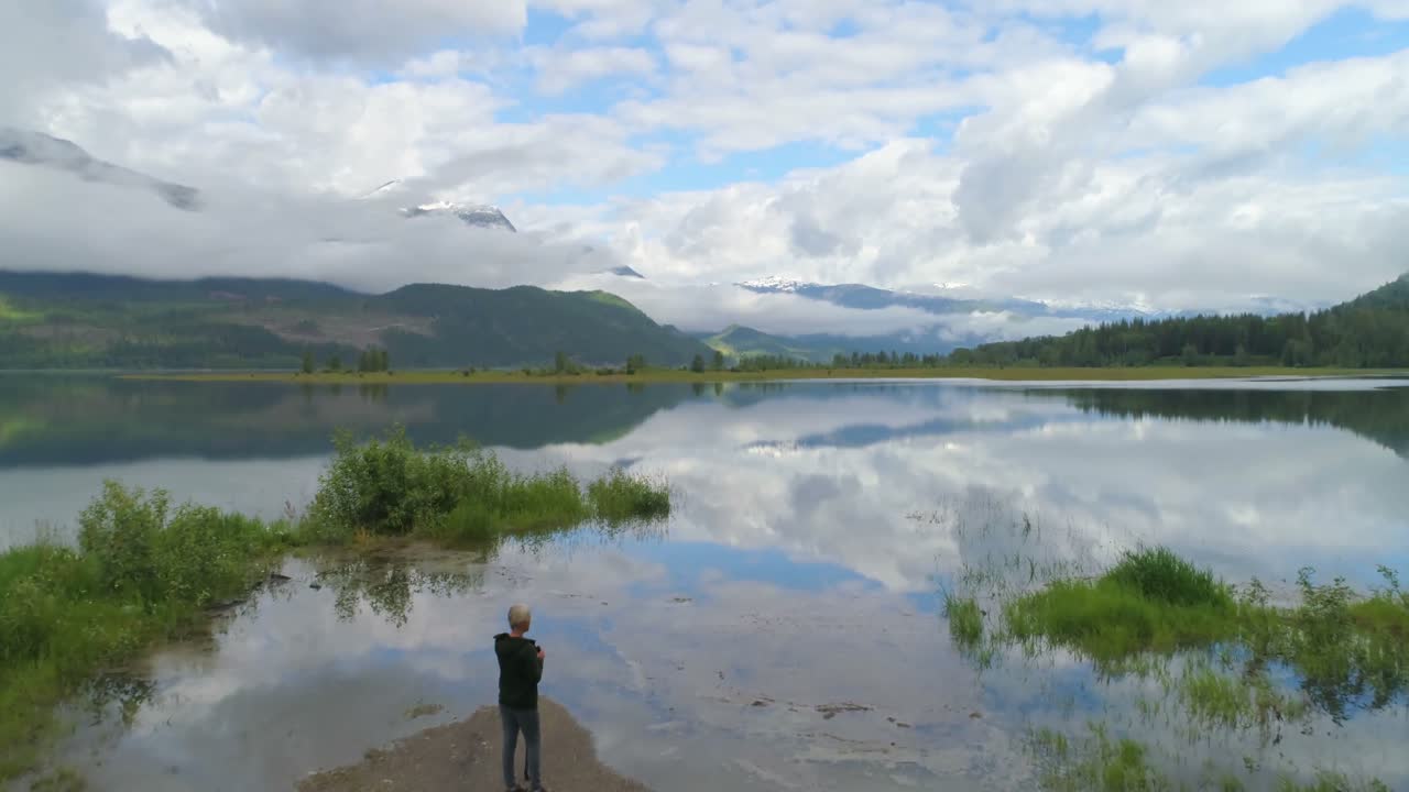 vista aérea de una mujer madura de pie cerca de un lago 4k