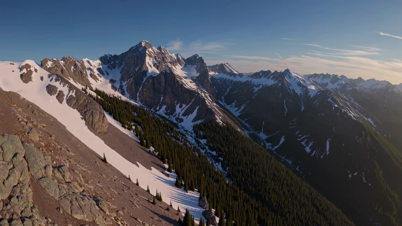 Aerial video captures a breathtaking panoramic view of snow-capped mountains and lush forests