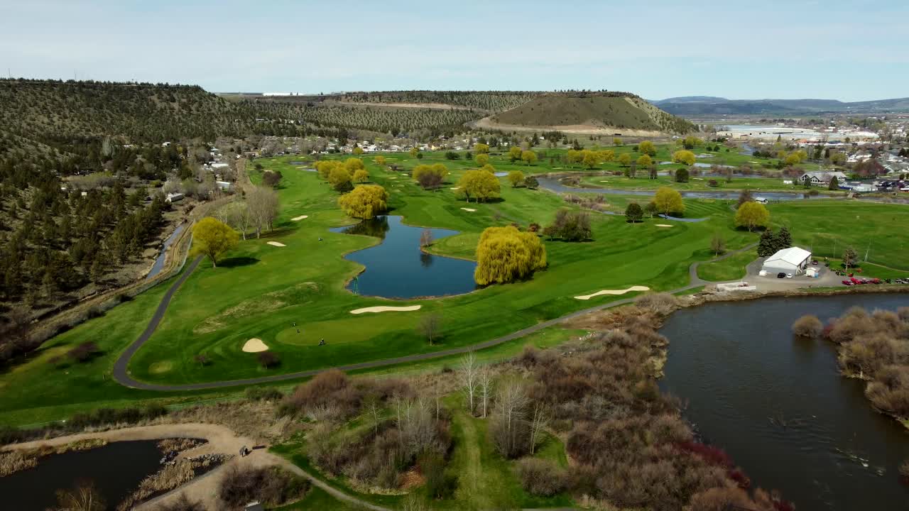 US, Oregon, Prineville, , 2025-04-11 - Drone view of a steel pedestrian bridge at Rimrock Park and the Crooked River at a golf course in spring in central Oregon