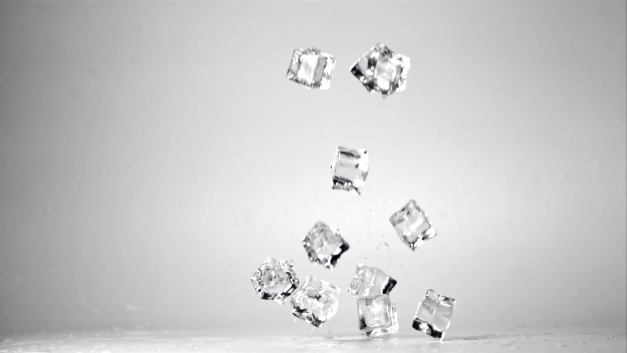 Cubetti di ghiaccio che cadono e rimbalzano al rallentatore su uno sfondo bianco
