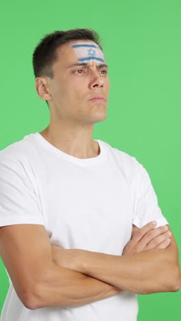 Man with israeli flag painted looking away with serious expression
