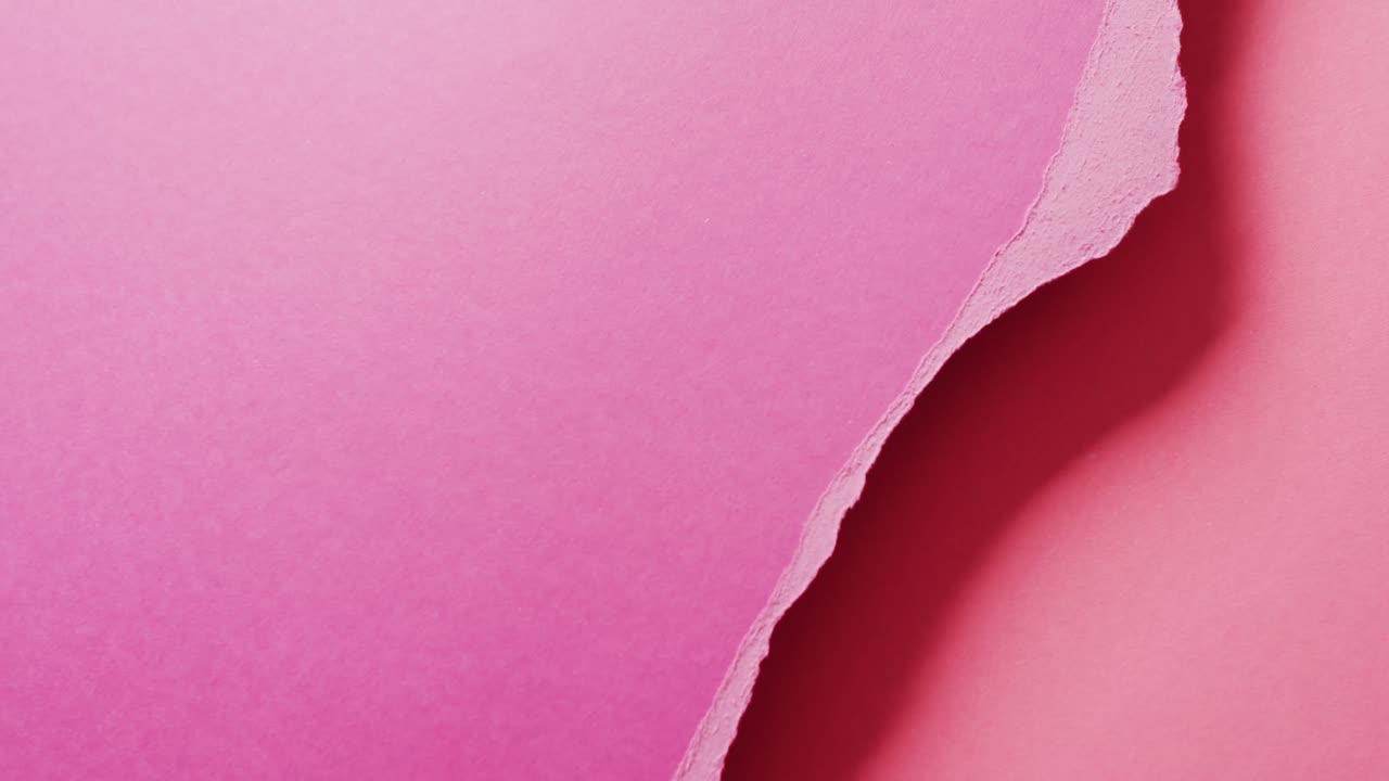 Video in primo piano di pezzi strappati di carta rosa con spazio per il testo come sfondo.