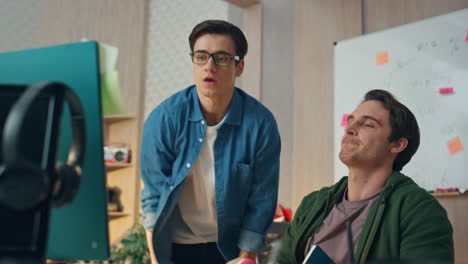 hombres de negocios celebrando el éxito mirando monitor de cerca. creadores dando cinco