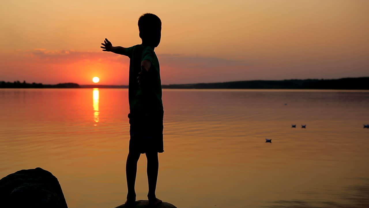 Paper Ship In Children Hand. Little boy launch paper ship on the water