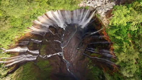 La-Impresionante-Cascada-Tumpak-Sewu-Desde-Arriba-En-Este-Metraje-Aéreo-De-4k-Con-Drones,-Capturando-Su-Grandeza-Mientras-Cae-En-Cascada-Por-Acantilados-Empinados-En-Medio-De-Una-Exuberante-Vegetación.