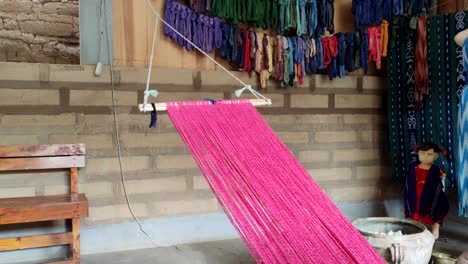 traditional hand weaving process on a loom with red threads