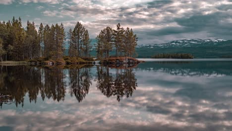 pink-gray fastmoving clouds lit by the setting sun reflected in the mirrorlike waters of the lake