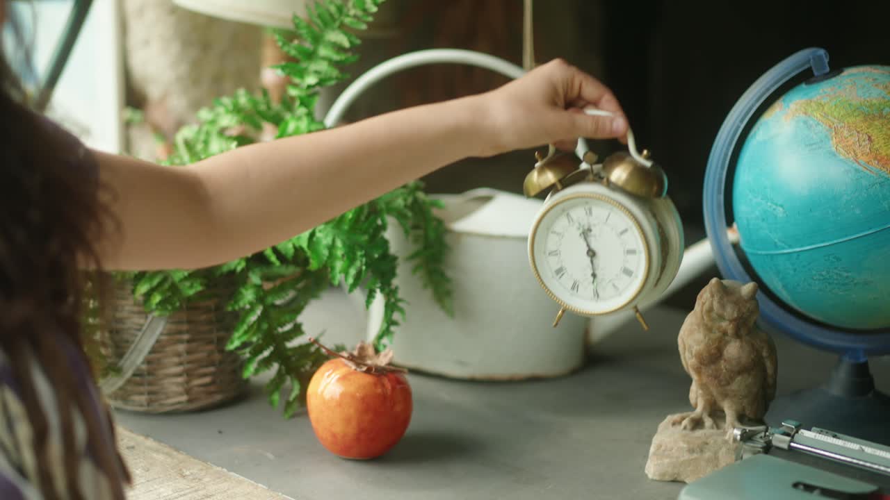 собирает в руки старинный будильник