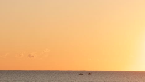 Zwei-Kleine-Boote-Auf-Dem-Meer,-Hinterleuchtet-Vom-Sonnenaufgang