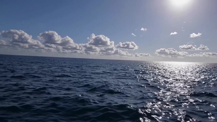 Riflesso della luce solare sulle calme onde dell'oceano sotto un cielo nuvoloso