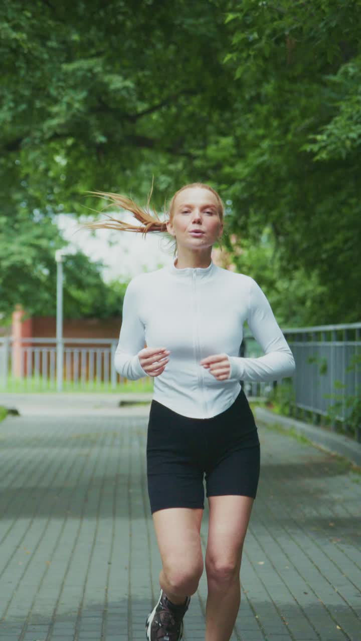 Una giovane atleta eccelle nella sua routine di corsa, mostrando dedizione e forma fisica in un ambiente naturale di parco verde in una giornata limpida.