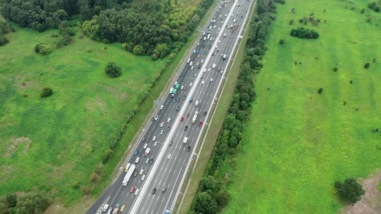 Top down aerial view of highway with traffic jam at rush hour, green nature around