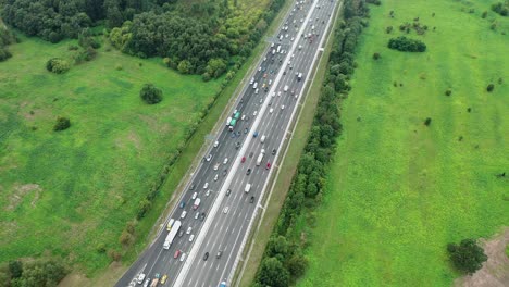 top down aerial view of highway with traffic jam at rush hour, green nature around
