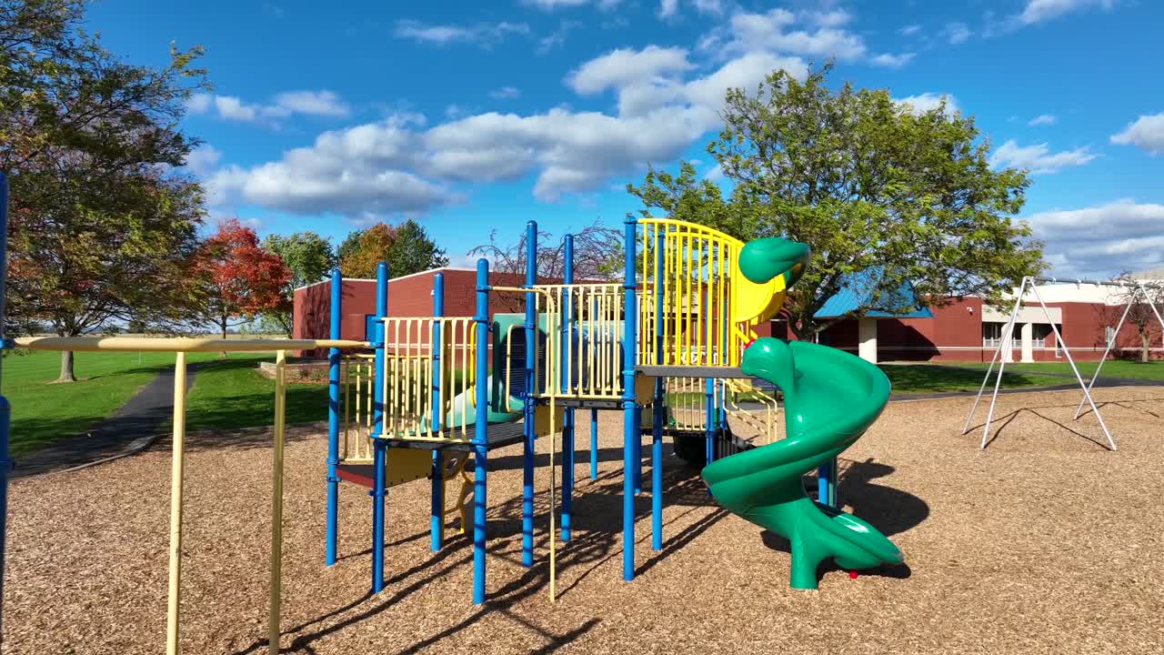 Colorful playground with slides and swings, sunny day, school in background