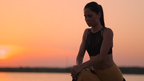 A-woman-performs-sit-UPS-at-sunset-on-the-beach-in-slow-motion.-Exercise-the-muscles-of-the-hips