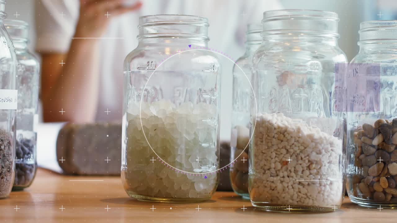 Man raising smartphone and comparing jars on table, HUD overlays labeling granules for tech demo