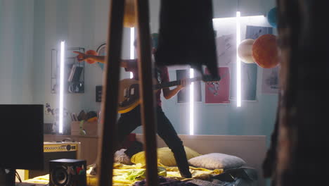boy playing guitar on bed in a colorful room