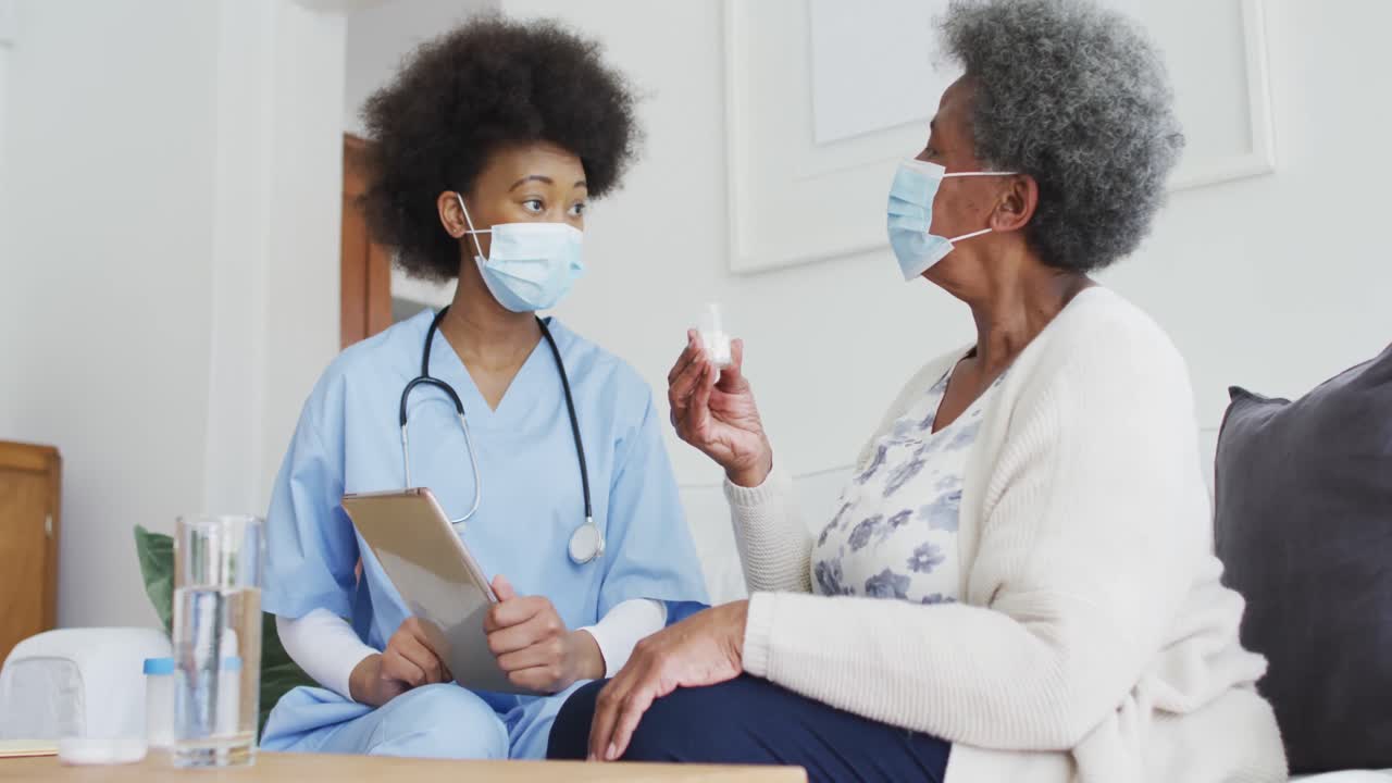 Femme médecin afro-américaine et patiente âgée portant des masques de protection.