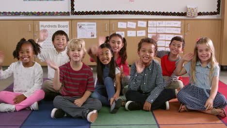 young elementary school class sit waving to camera