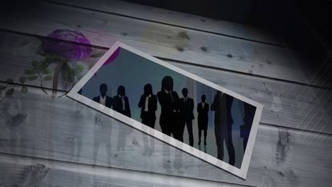 Animation-of-businesspeople-silhouettes-on-photo-over-wooden-surface