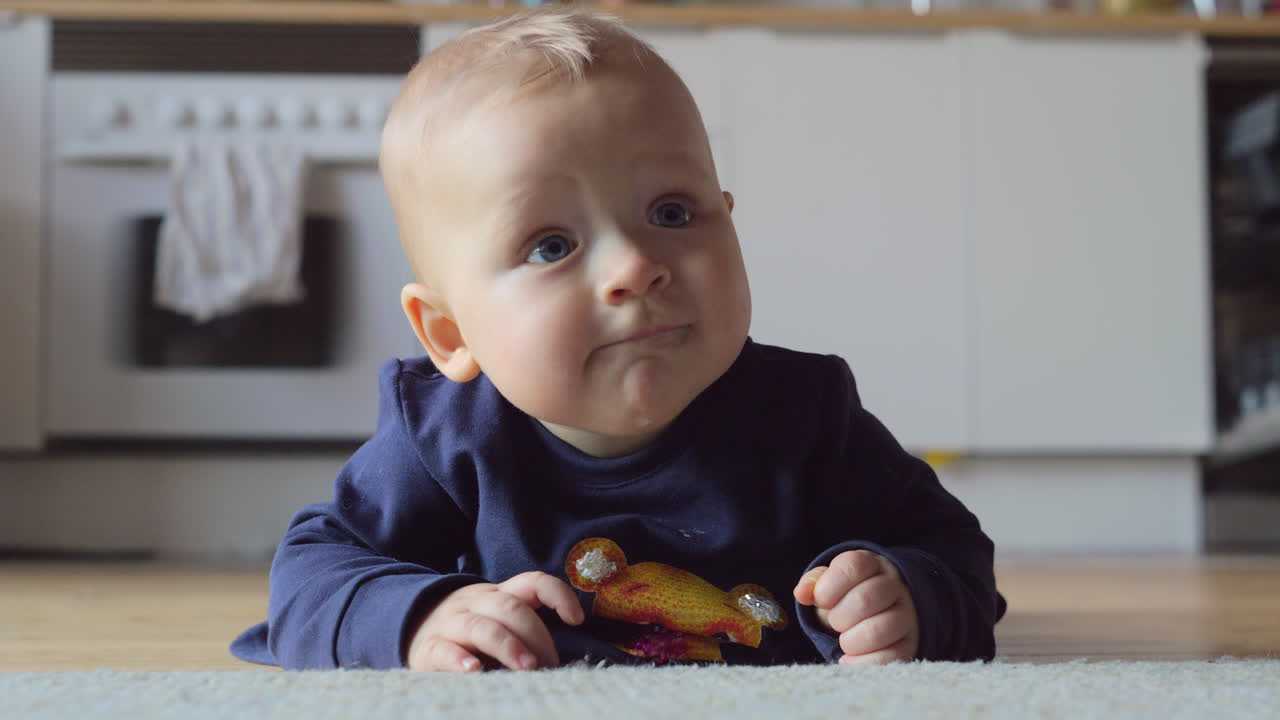 Baby girl in blue clothes playing on the carpet