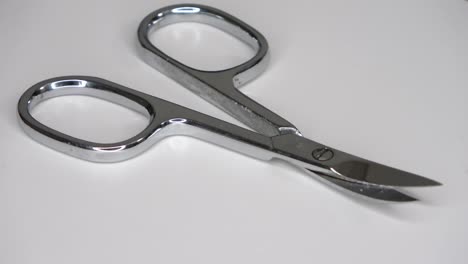 loopable selective focus of small metal scissors spinning on white background.