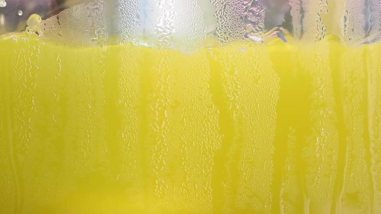 Close-up of Cold Yellow Juice in Glass with Condensation