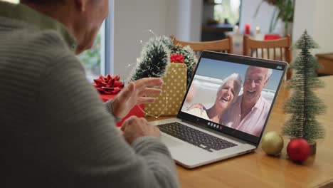 Happy-caucasian-senior-man-on-video-call-with-senior-friends-at-christmas-time