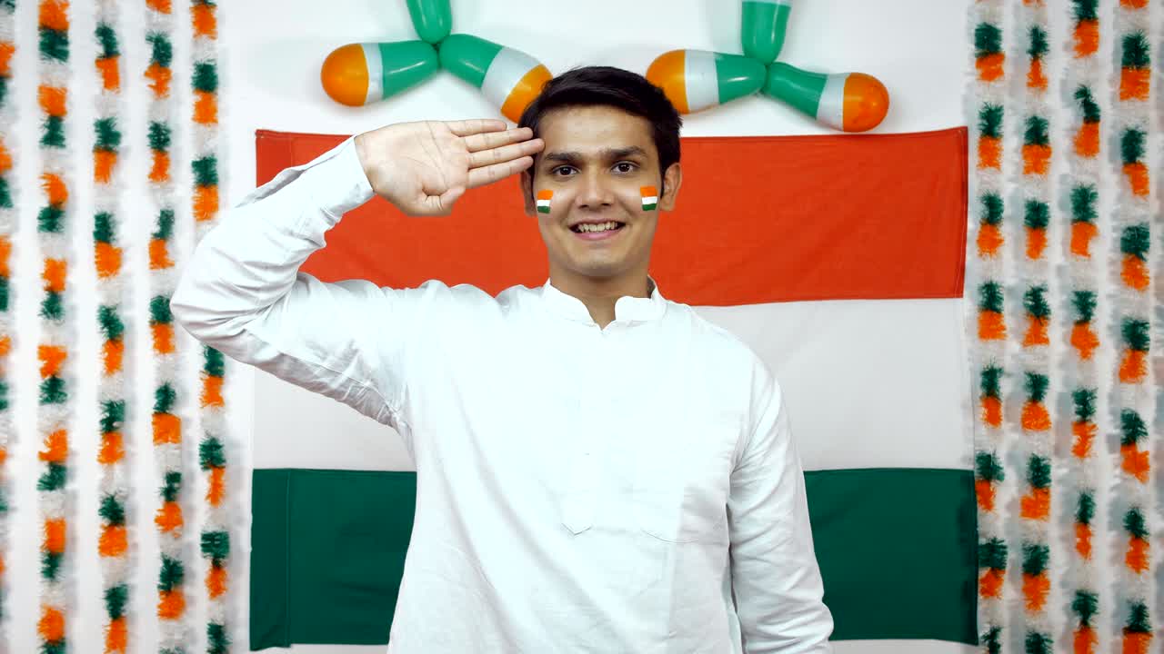 Ragazzo indiano che saluta rivolto verso la telecamera. Sfondo tricolore - Giorno dell'Indipendenza