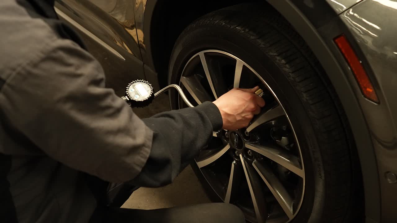 Mechanic checking tire air pressure, panning shot