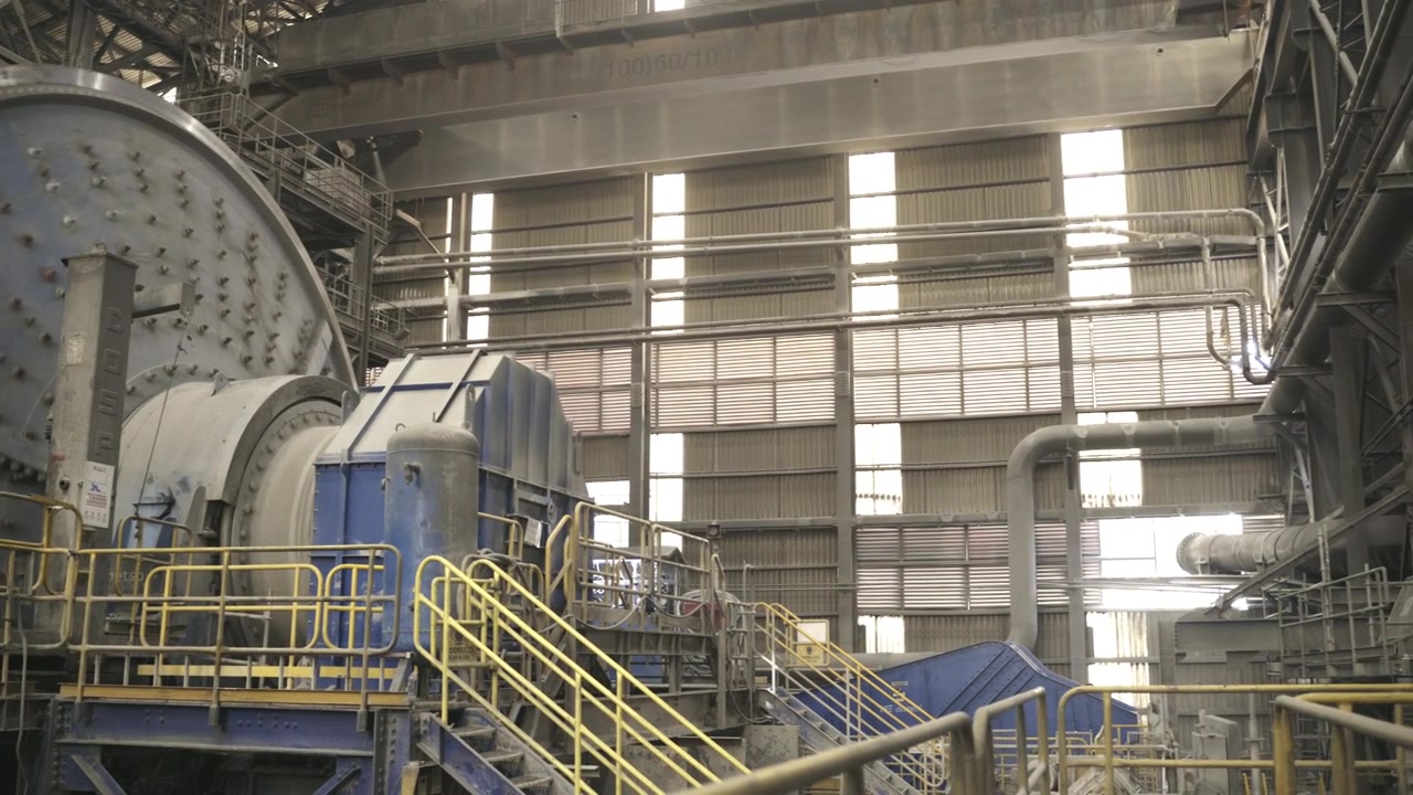 Industrial grinding mill operating inside a large copper processing facility. The footage showcases mineral processing technology, heavy machinery, and large scale mining operations.