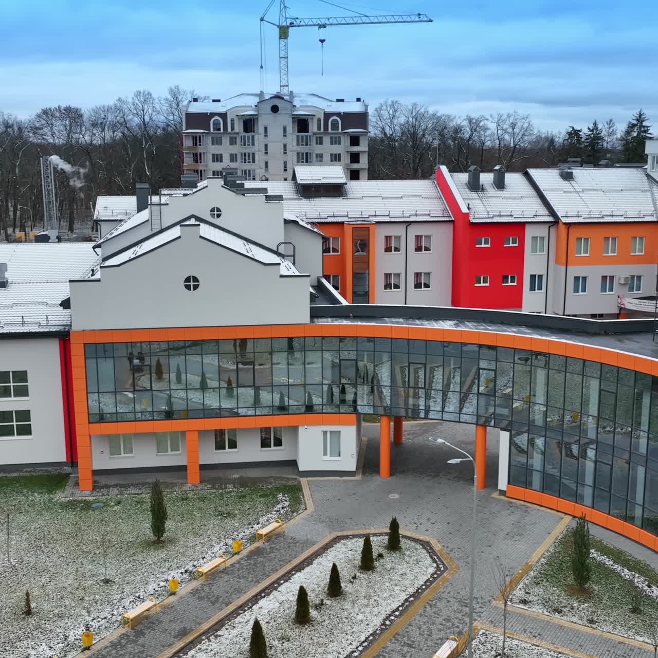 Bright exterior of a new school building. Modern architecture decisions in urban construction. Trees and apartment blocks at the backdrop