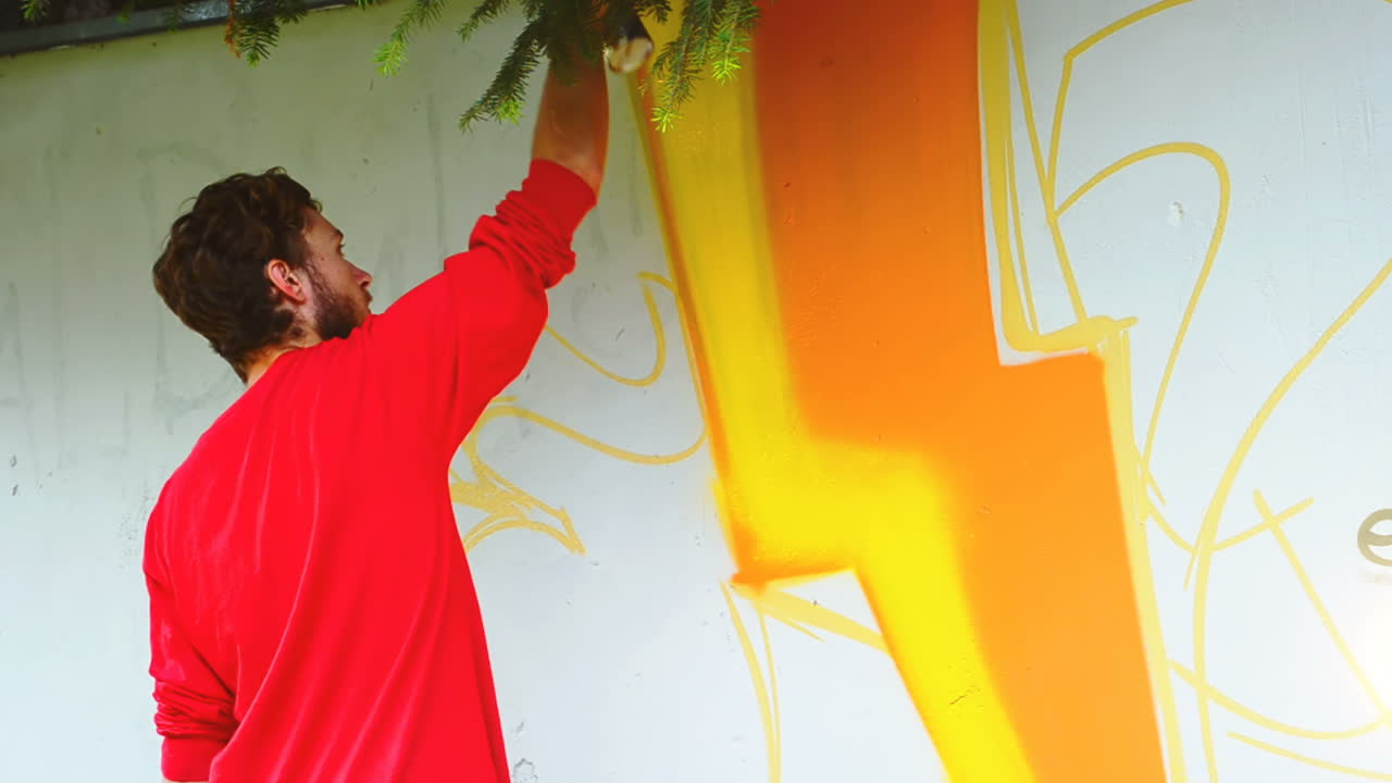L'artista realizza graffiti su una recinzione. Disegno astratto