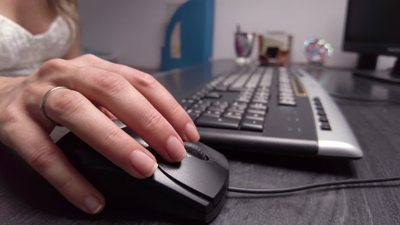 Close up of a woman clicking on a mouse while working on a computer