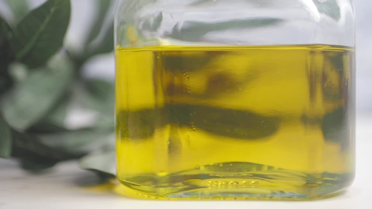 Olive Oil Pouring into Glass Bottle