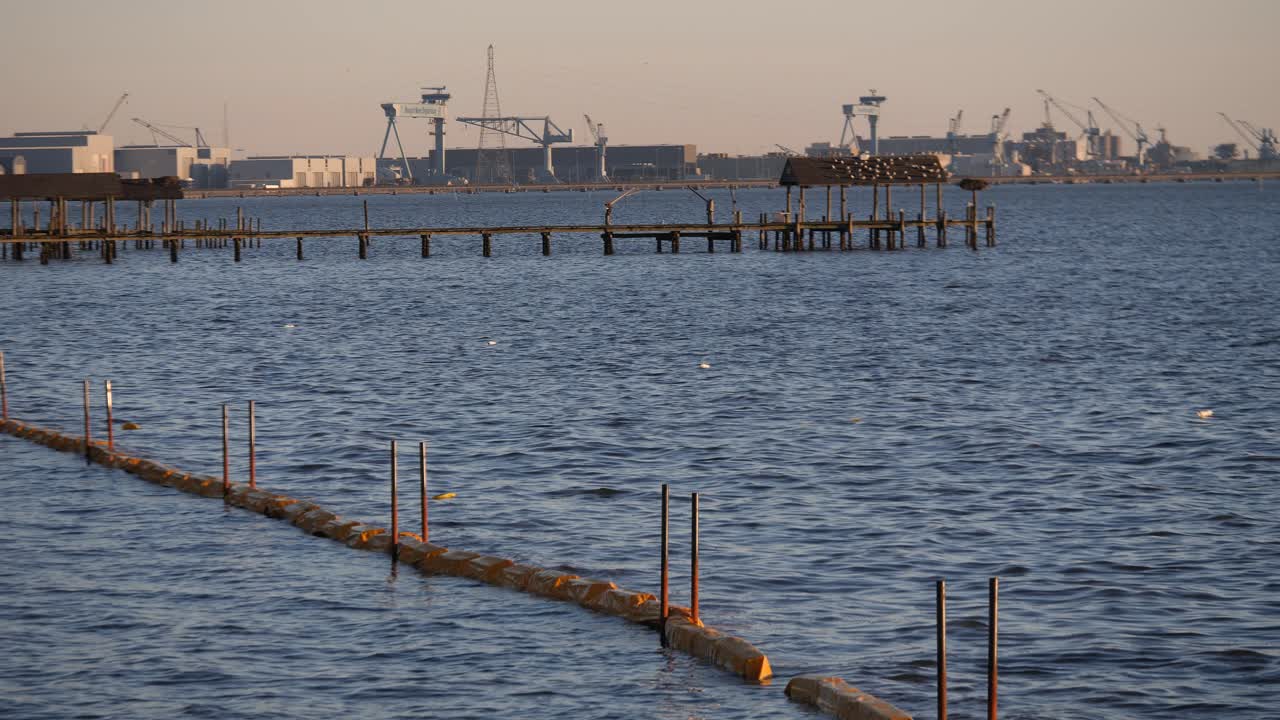 Protective barrier floating on sea water, pier and port area beyond
