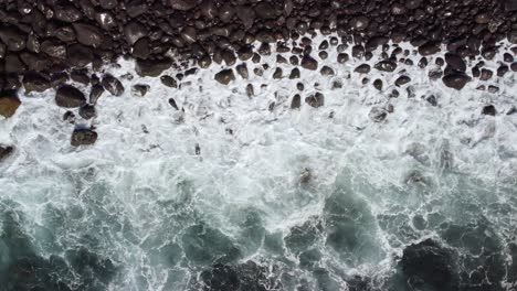 blue wave rolling in and out of pebble beach creating abstract patterns