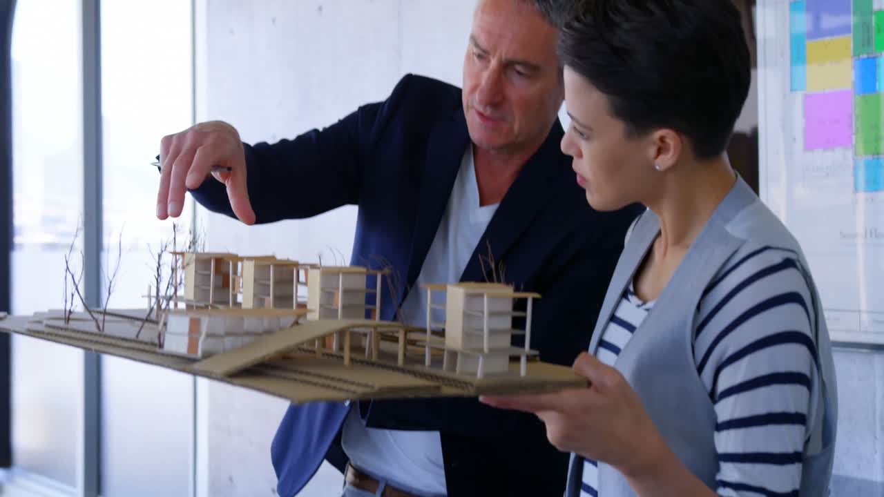 hombres de negocios caucásicos discutiendo sobre el modelo de fábrica en la oficina moderna 4k