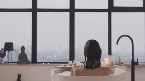 rear view of a woman taking a bath in a bathtub filled with water and foam