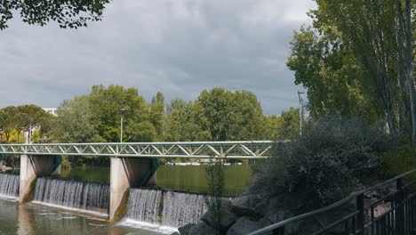 Move-to-the-bridge-over-the-small-waterfall,-Montpellier---France