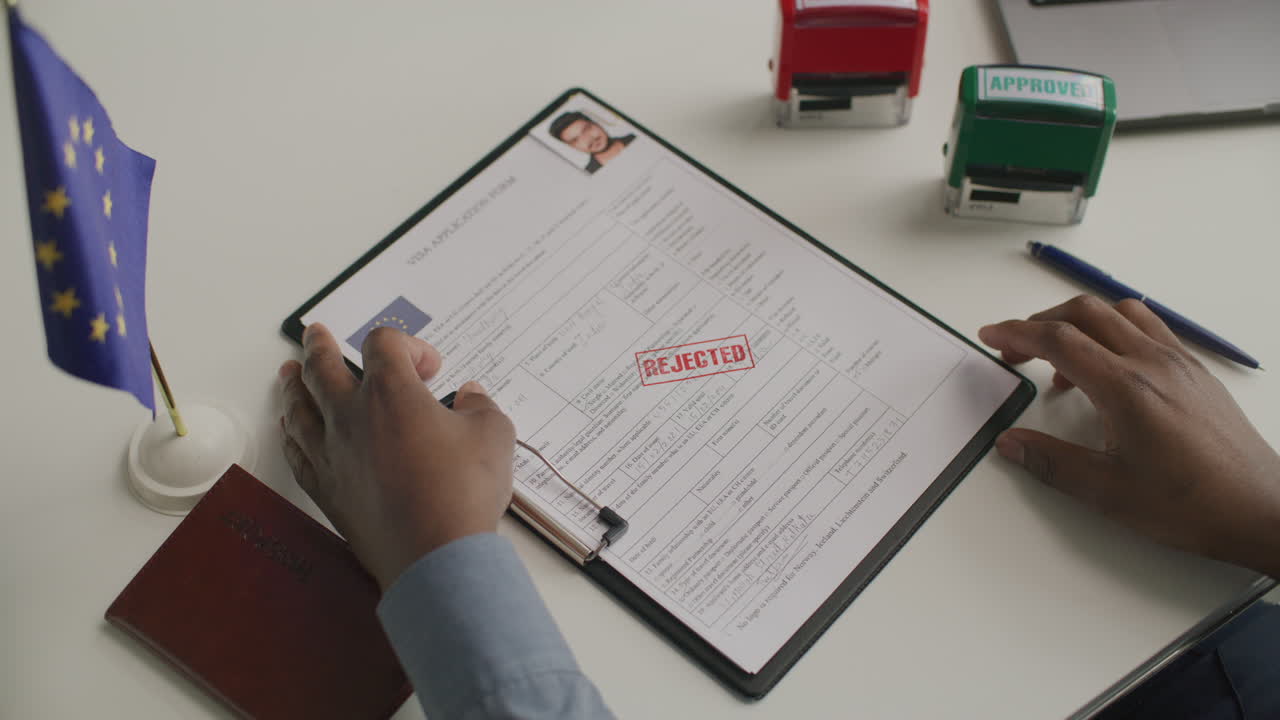 Hands of Visa Officer Stamping Rejection Mark on European Visa Application