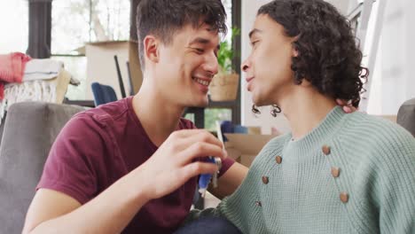 Happy-diverse-male-moving-house,-holding-keys,-embracing-and-smiling