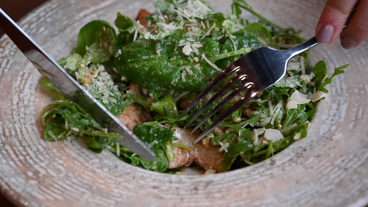 Close up of a woman eating a Caesar salad at a restaurant