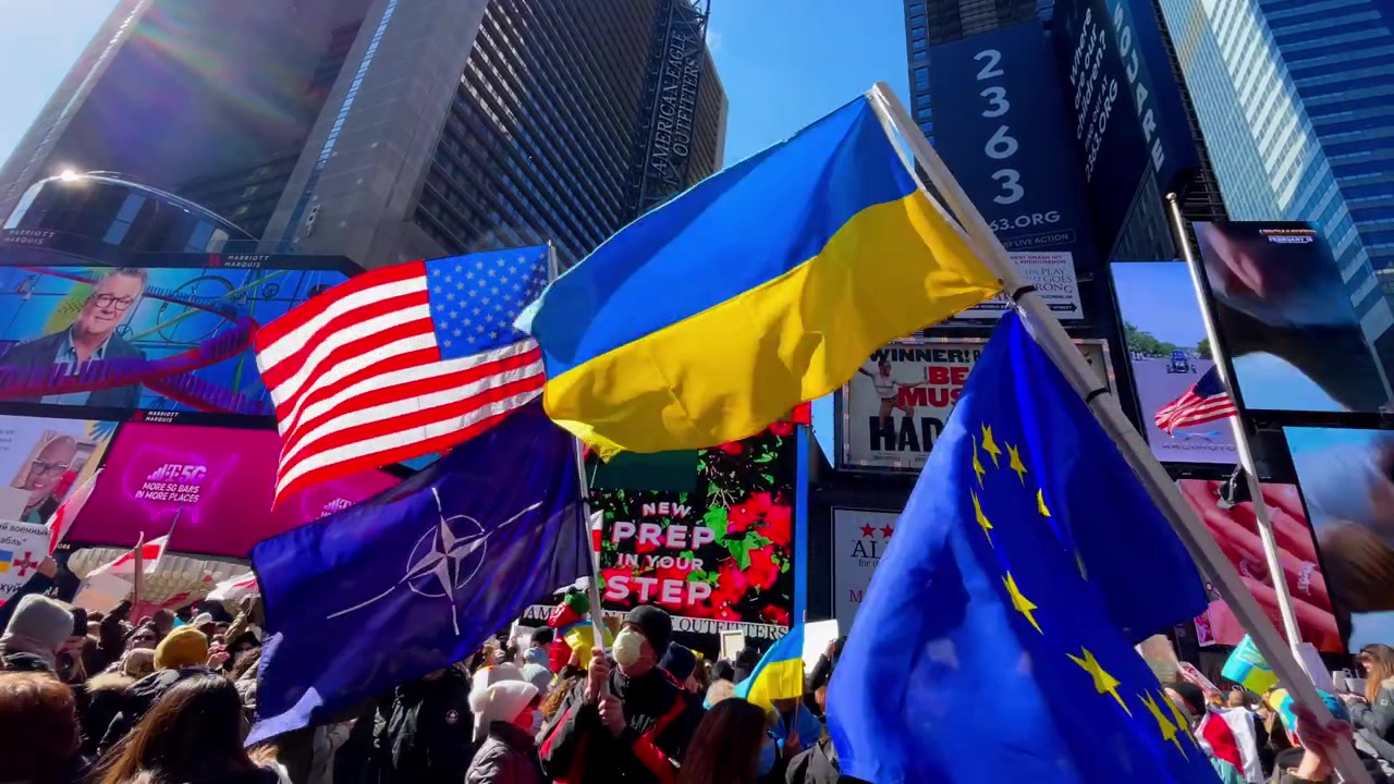 New York, USA, 9 March 2022: Rally with Ukrainian and American flags in Times Square. Crowd of people waving Ukraine, USA, and EU flags during a demonstration in Times Square, New York City.