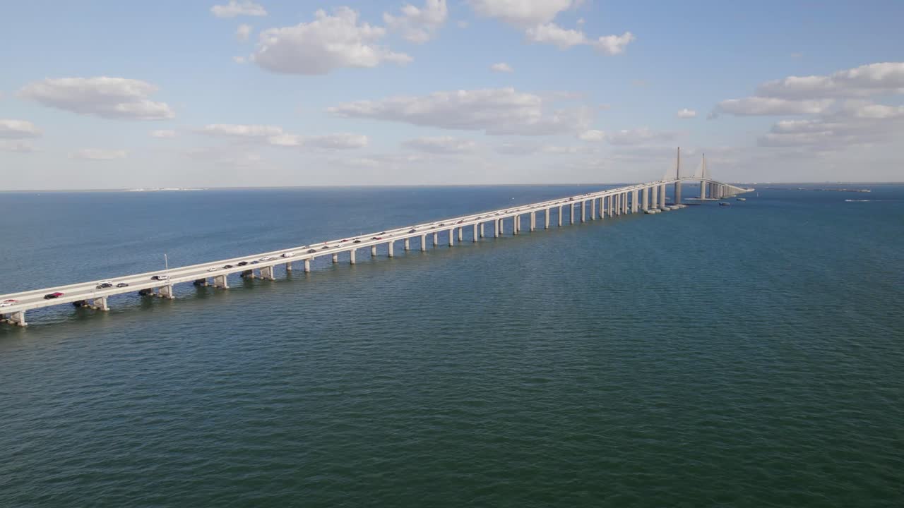 A stunning bird's-eye view of the Sunshine Skyway Bridge stretching across the waters of St. Petersburg, Florida, on a clear, sunny day.