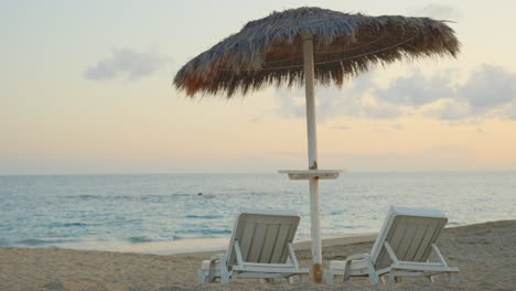 Summer-tropical-beach-luxury-vacation-scenery,-umbrella-and-empty-chairs,-sunset