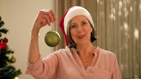 at christmas, senior woman in santa hat holding ornament, smiling joyfully at home