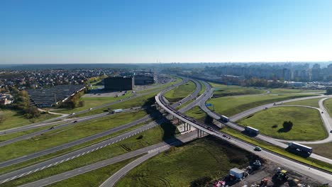 aerial view captures a a1 and a5 highway interchange near the mega shopping mall in kaunas, lithuania, showcasing the smooth flow of traffic under a bridge during daytime