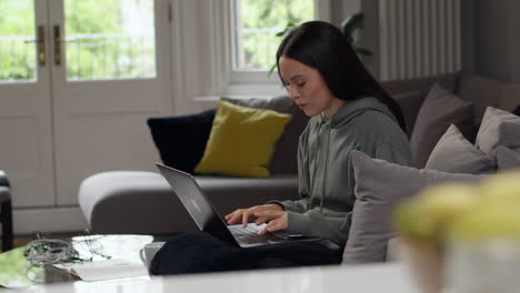 anxious woman sitting indoors on sofa working from home using laptop worried about cost of living crisis 3